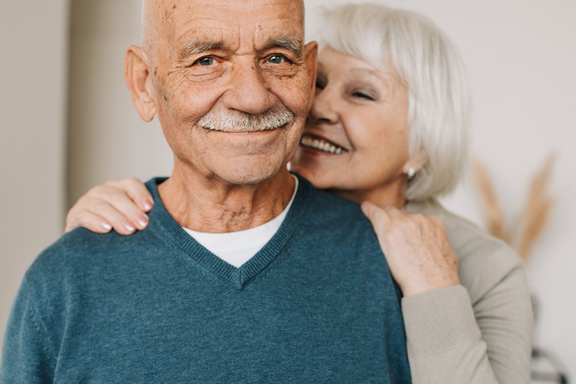 An older couple smiling warmly together at home.